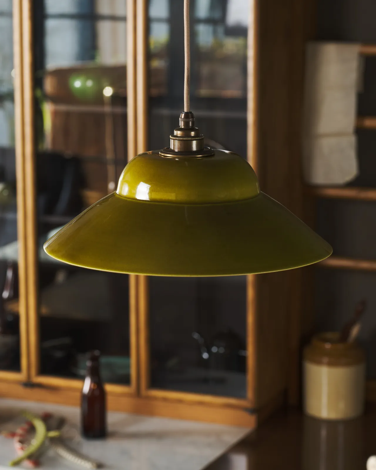 A close-up oblique view of a mid-century-style chartreuse glazed ceramic light shade.