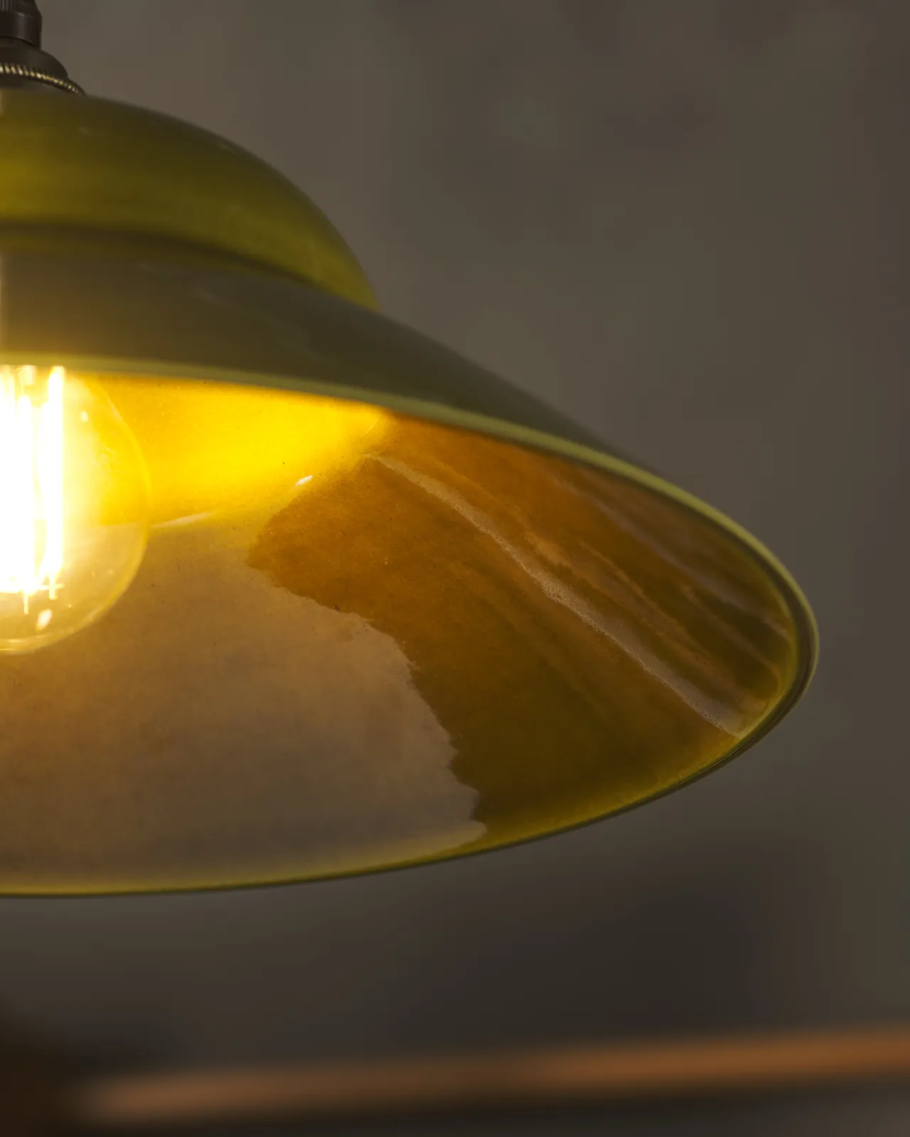 A close-up view of the underside of a mid-century-style chartreuse glazed ceramic light shade.