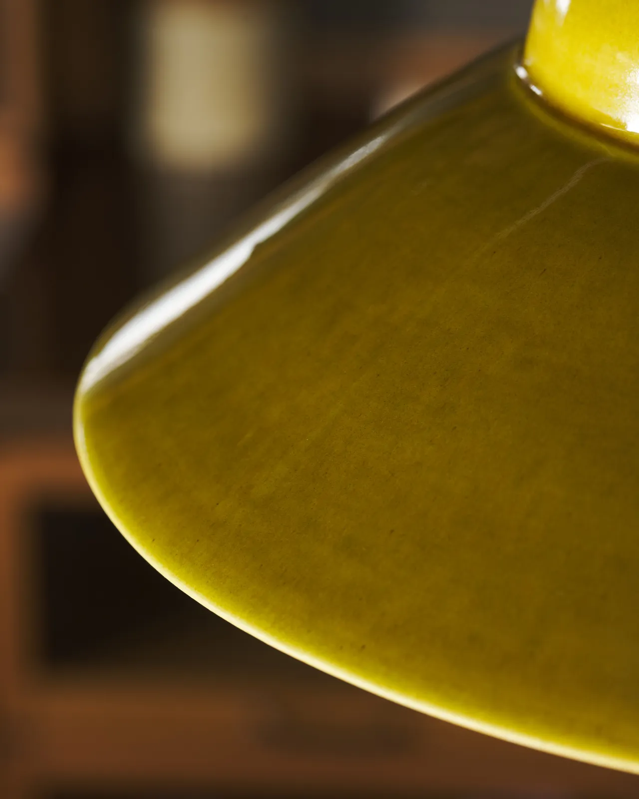 A close-up view of the rim of a mid-century-style chartreuse glazed ceramic light shade.