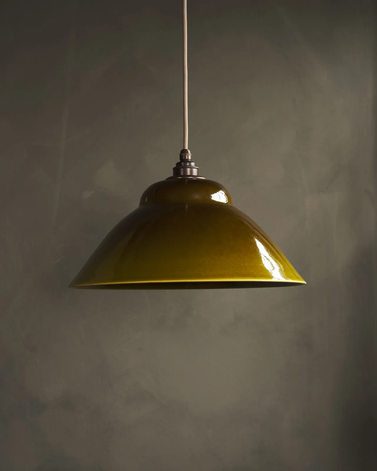A straight-on view of a mid-century-style sepia glazed ceramic pendant light, the light is off.