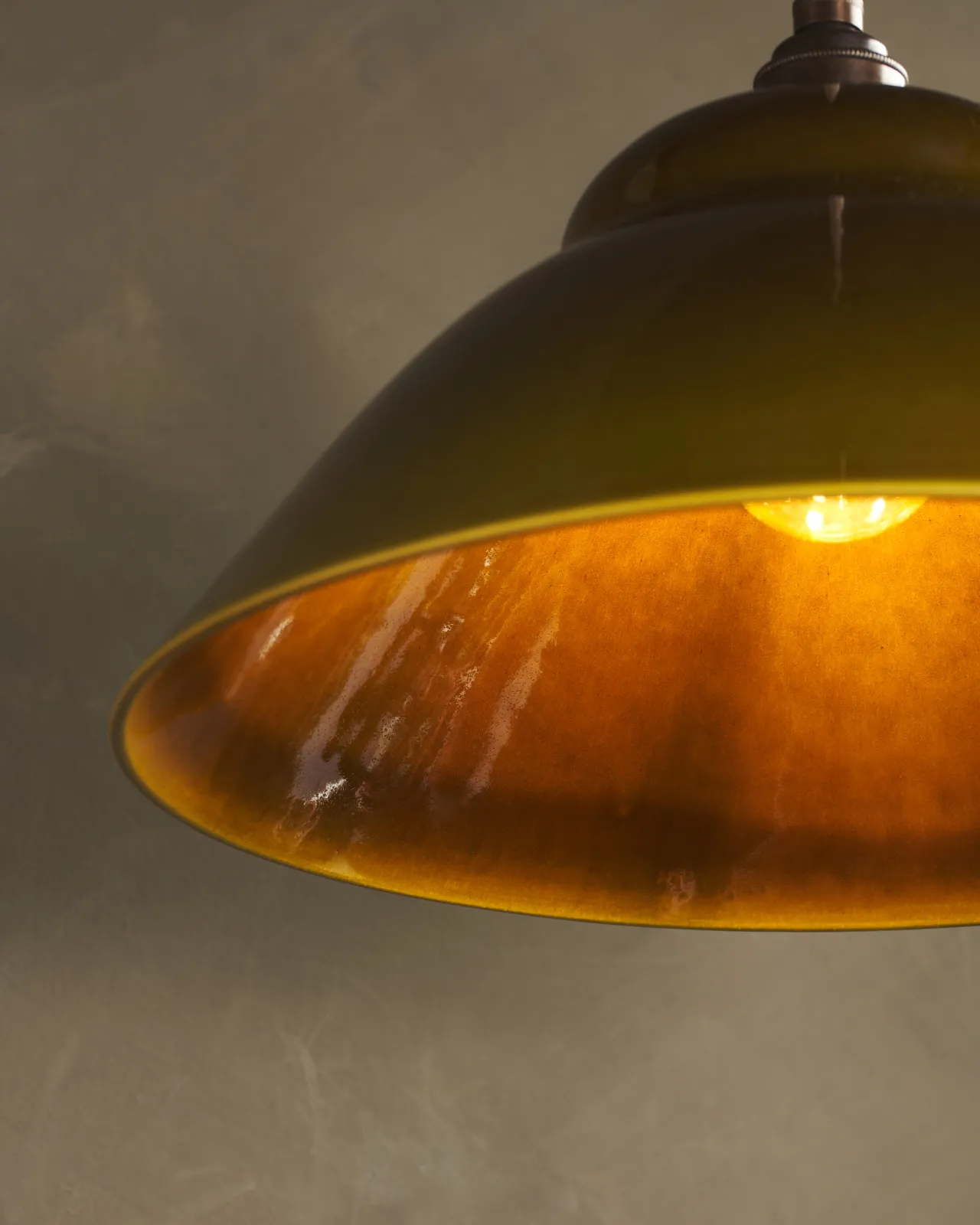 A close-up view of the underside of a mid-century-style sepia glazed ceramic light shade.