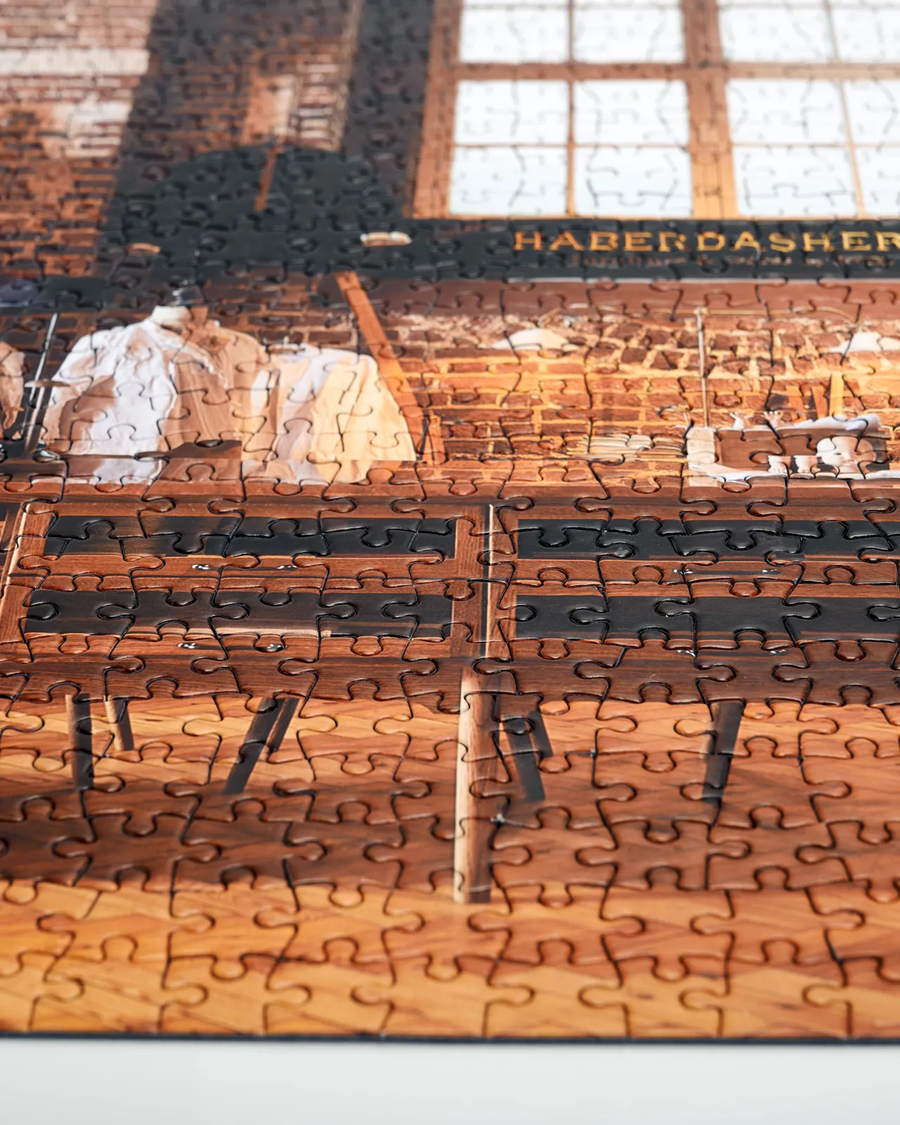 A close-up view of an assembled jigsaw puzzle of a mid-century-style oak kitchen in a red brick room with warm parquet wood flooring.