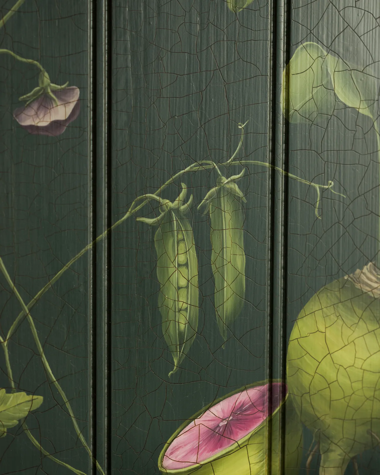 A close-up view of painted pea pods on a dark green tongue and groove back panel.