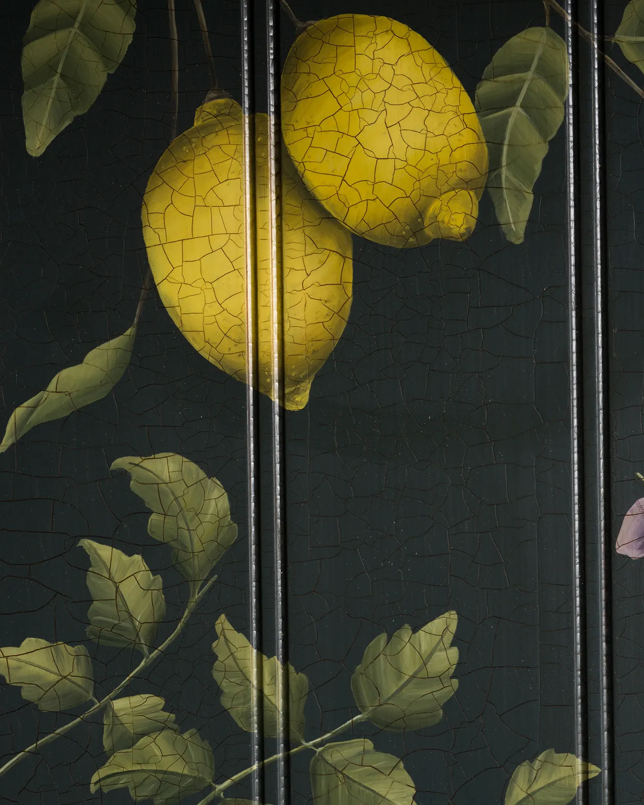 A close-up view of painted lemons on a dark green tongue and groove back panel.