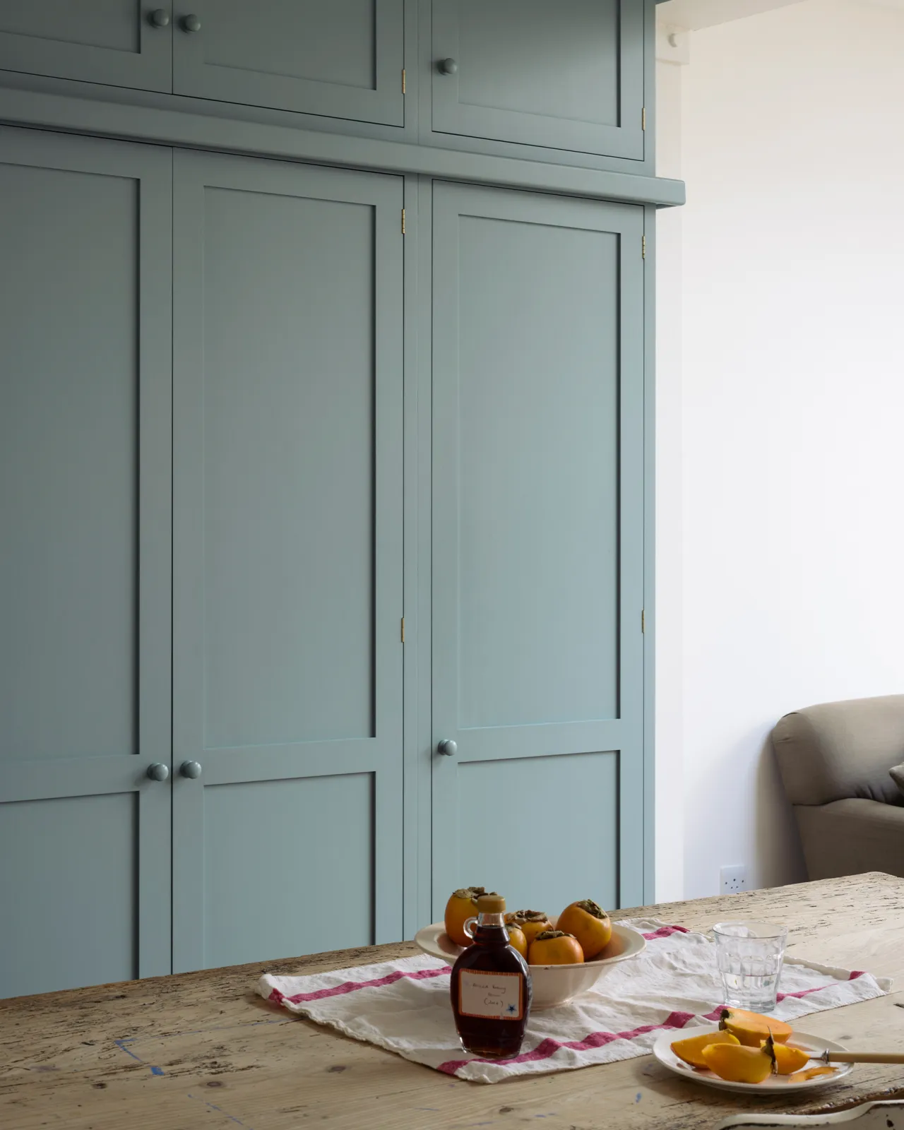 An oblique view of a tall bank of duck-egg blue painted Shaker-style pantry cupboards.