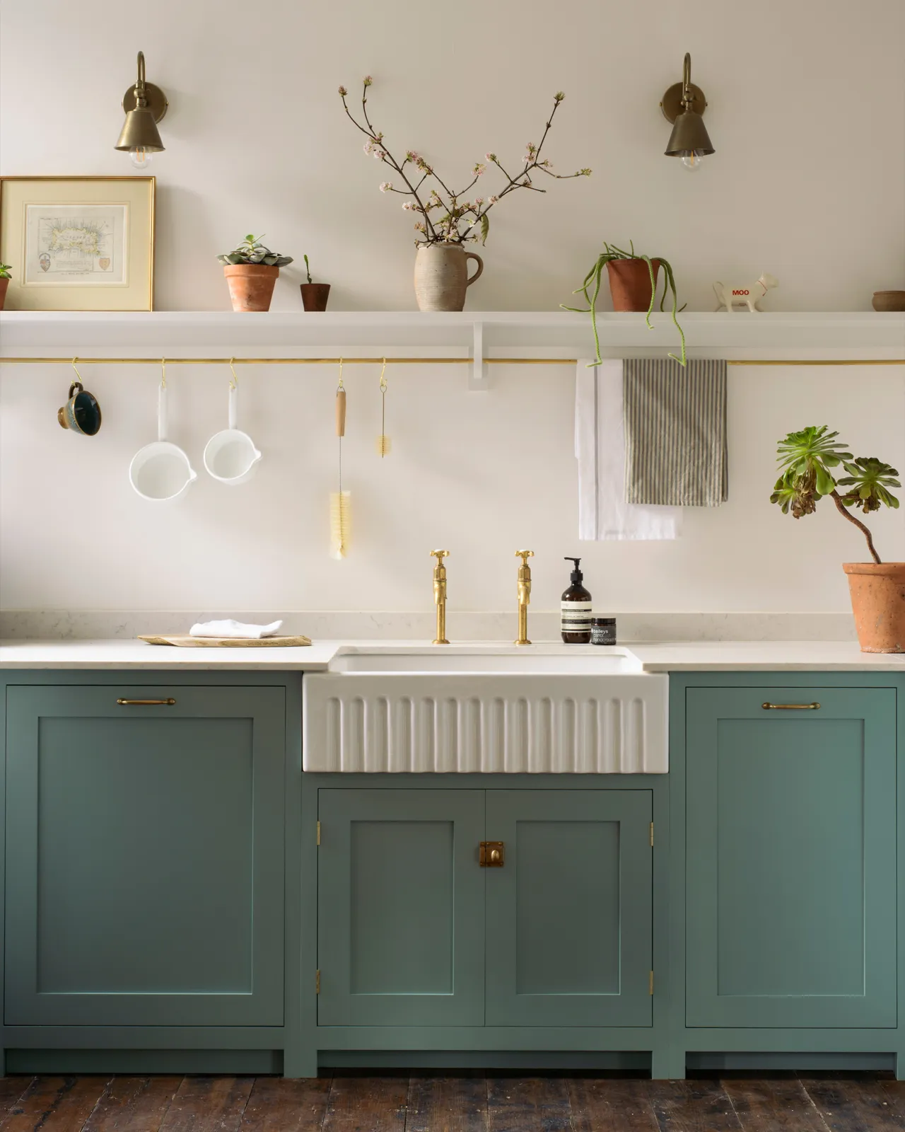 A straight-on view of a simple duck-egg blue painted Shaker-style kitchen with a fluted Belfast sink and white walls.