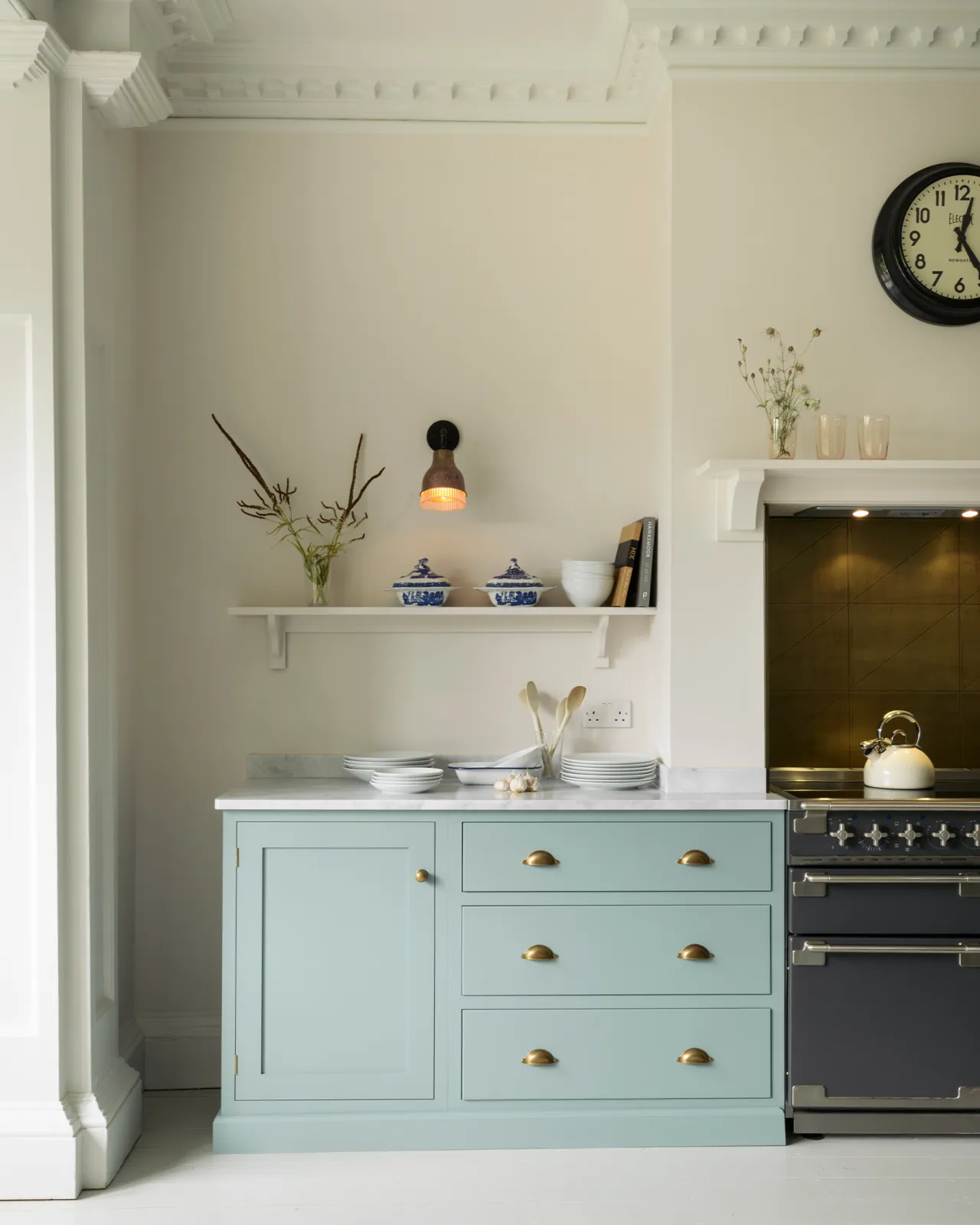 A straight-on view of duck-egg blue painted Shaker-style cupboards next to a black range cooker.