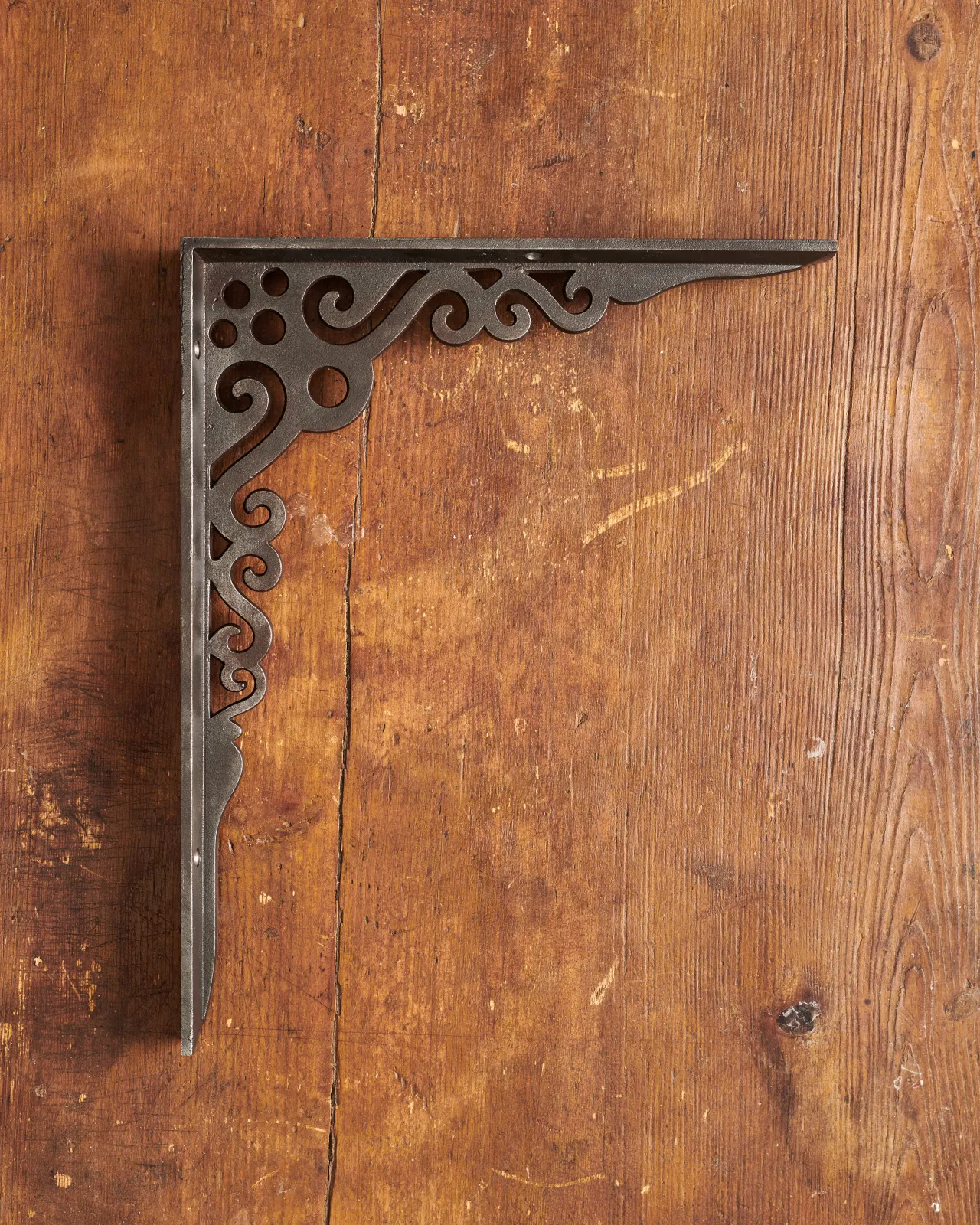 A side profile view of a large Victorian-inspired ornate shelf bracket in a cast iron finish.