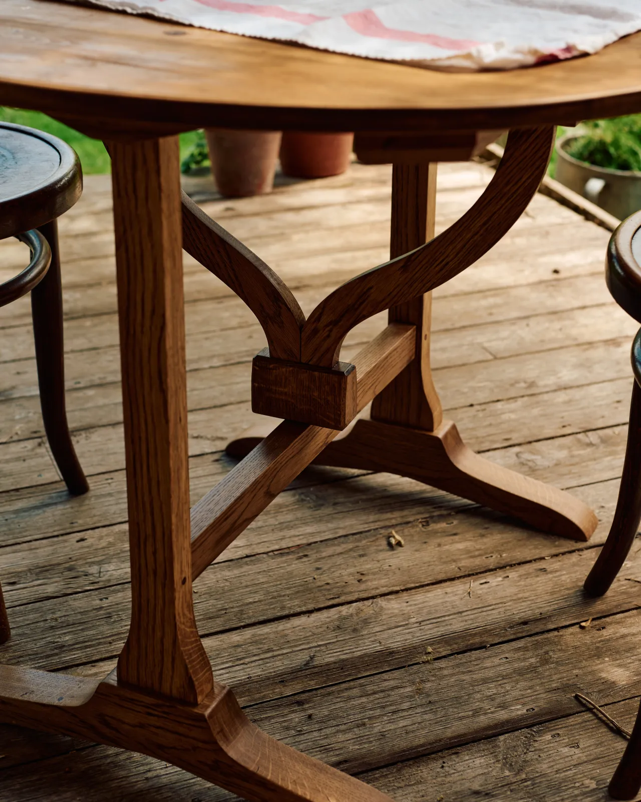 A close-up view of a simple turning support mechanism built into the frame of a small round pine dining table.