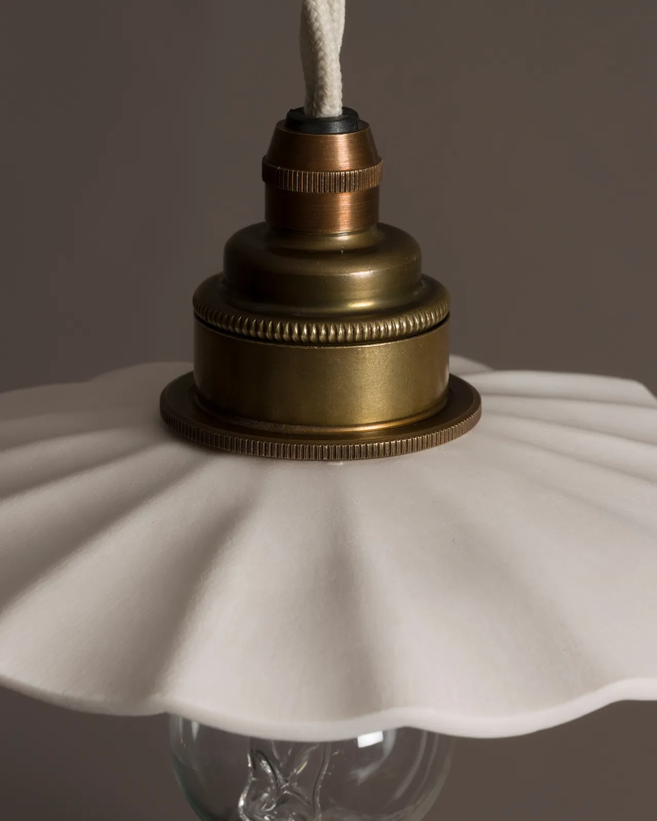 A close-up view of an unglazed porcelain pendant light with wide pleats.