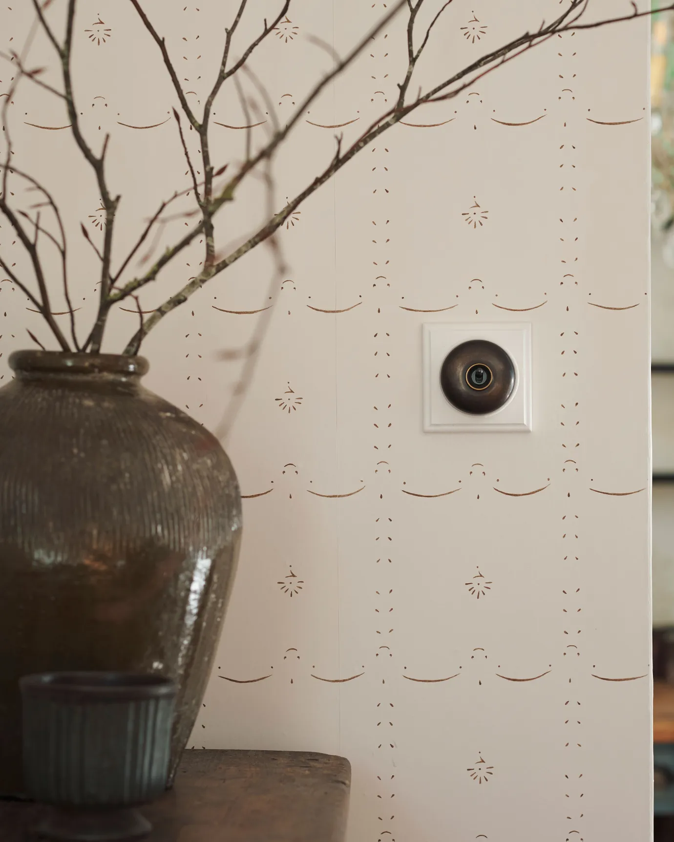 A 1 gang Dolly toggle light switch in an Oxidised Brass finish, with a black ceramic base and a painted maple pattress.