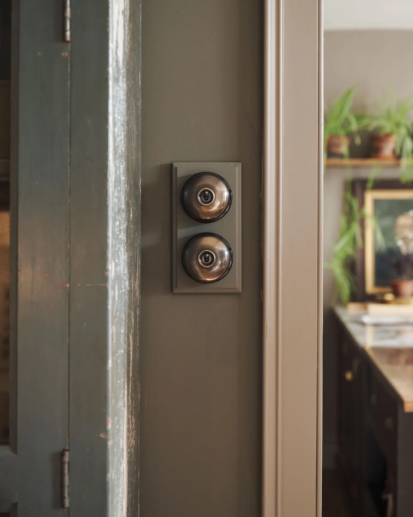 A 2 gang row of Dolly toggle light switches in an Oxidised Brass finish, with black ceramic bases and a painted maple pattress.