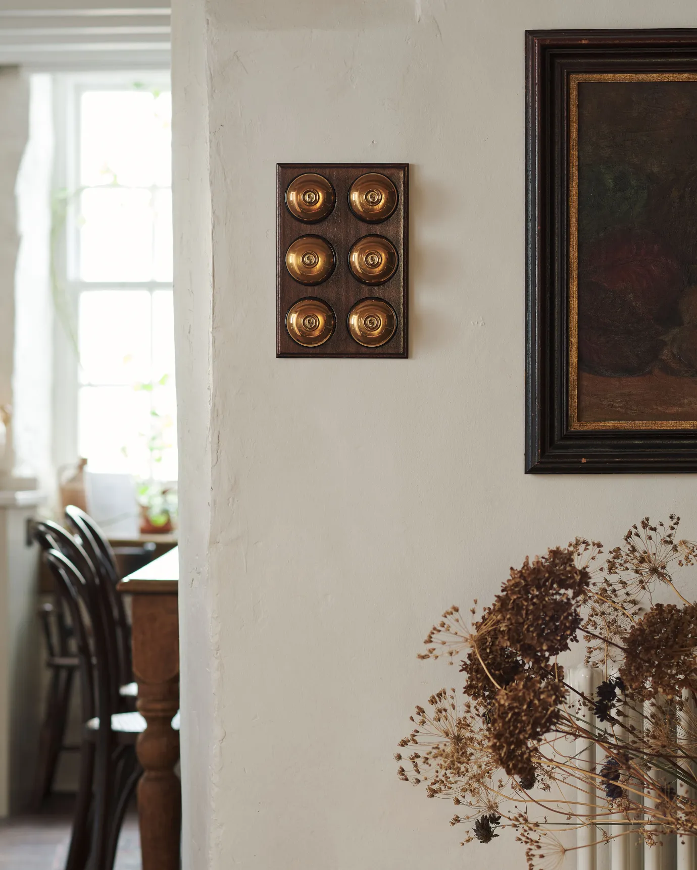 A 6 gang bank of Dolly toggle light switches in an Heirloom Brass finish, with black ceramic bases and a Stained Sapele pattress.