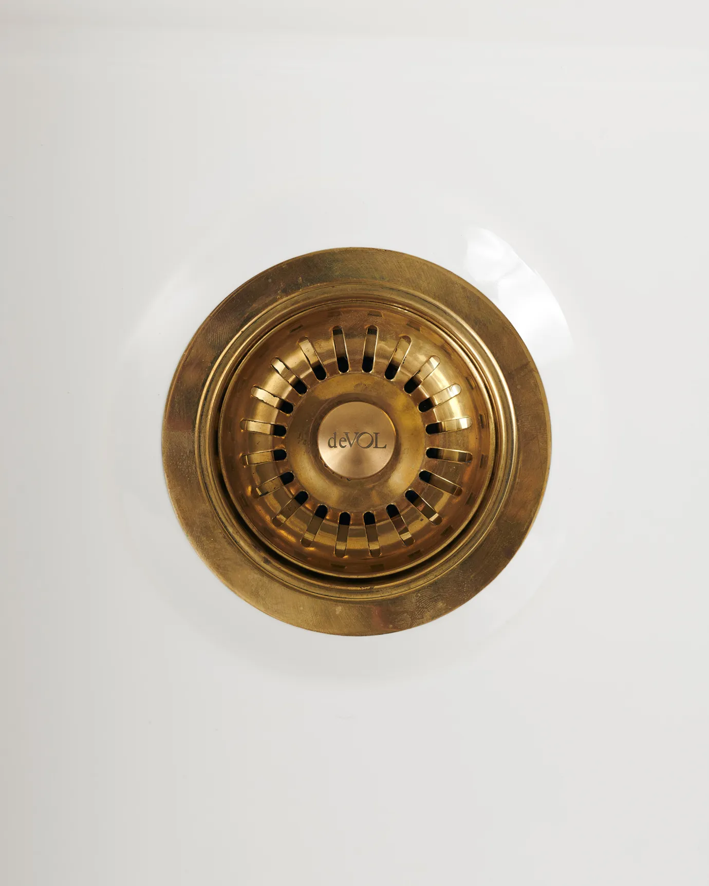 An overhead view of a basket waste strainer in a warm burnished brass finish, there is a small 'deVOL' logo in the middle of the central finial.