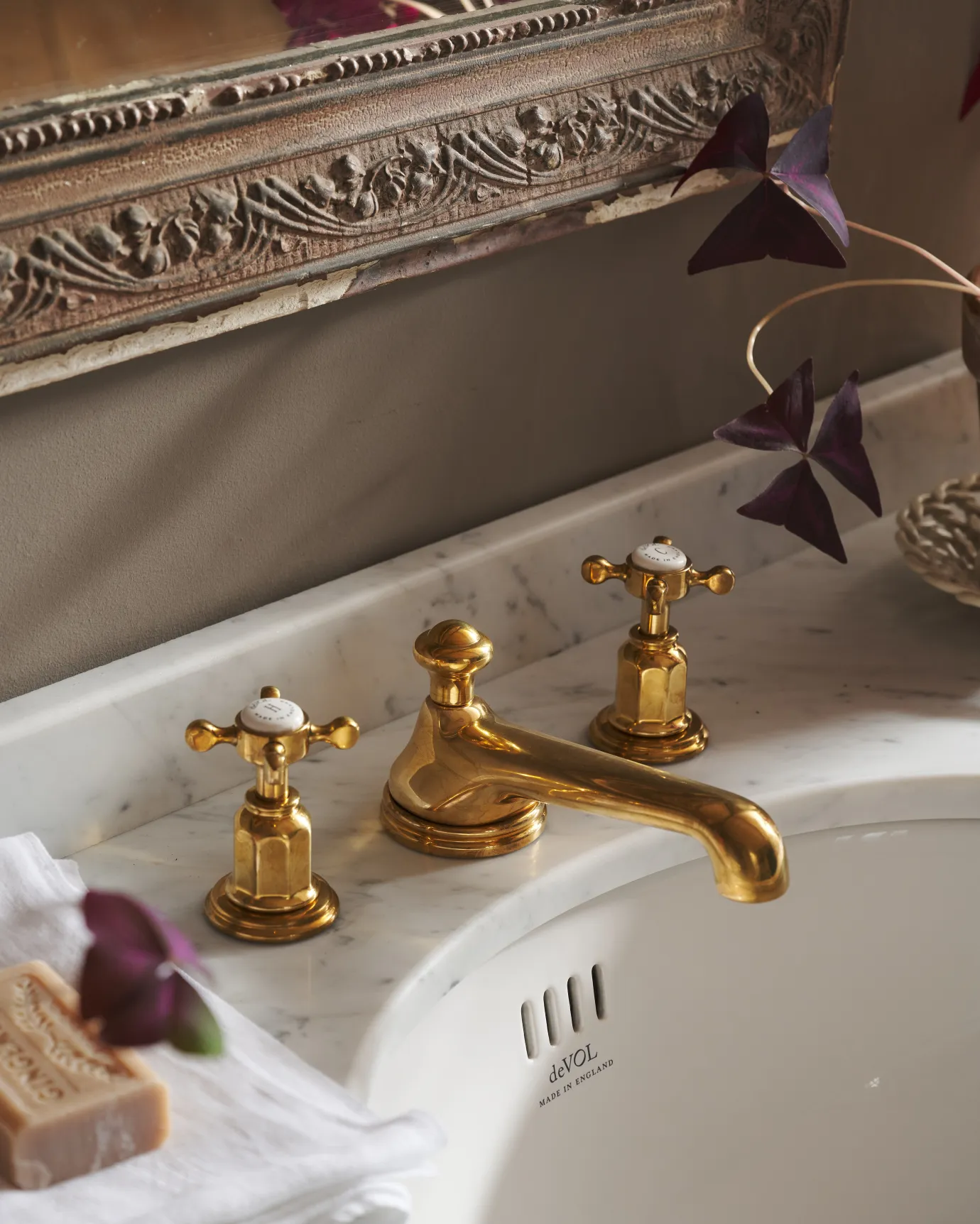 An oblique view of an aged brass mixer tap with crosshead handles for a bathroom basin sink.
