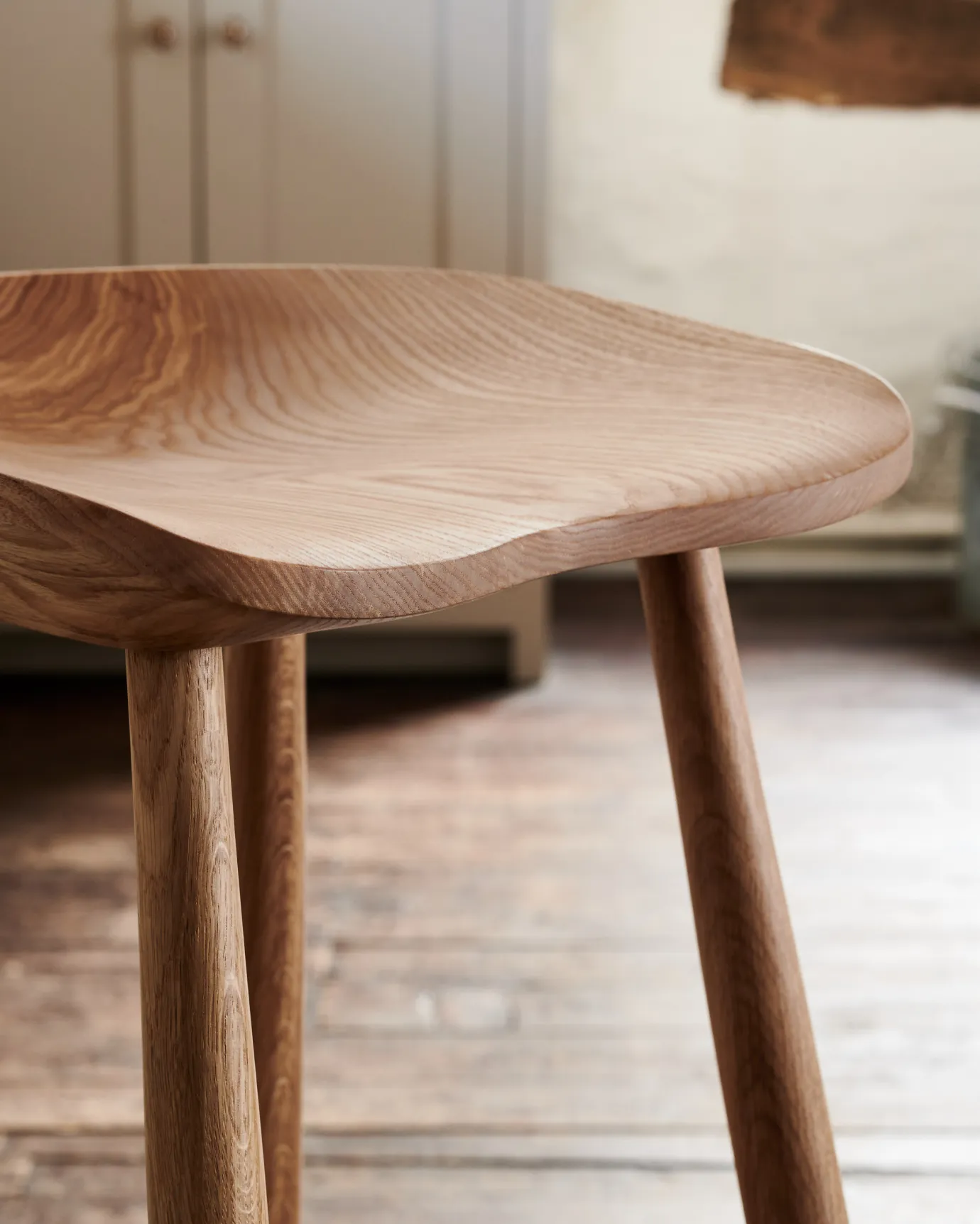 A close-up view of a sculpted ash seat pan from a mid-century-style bar stool.
