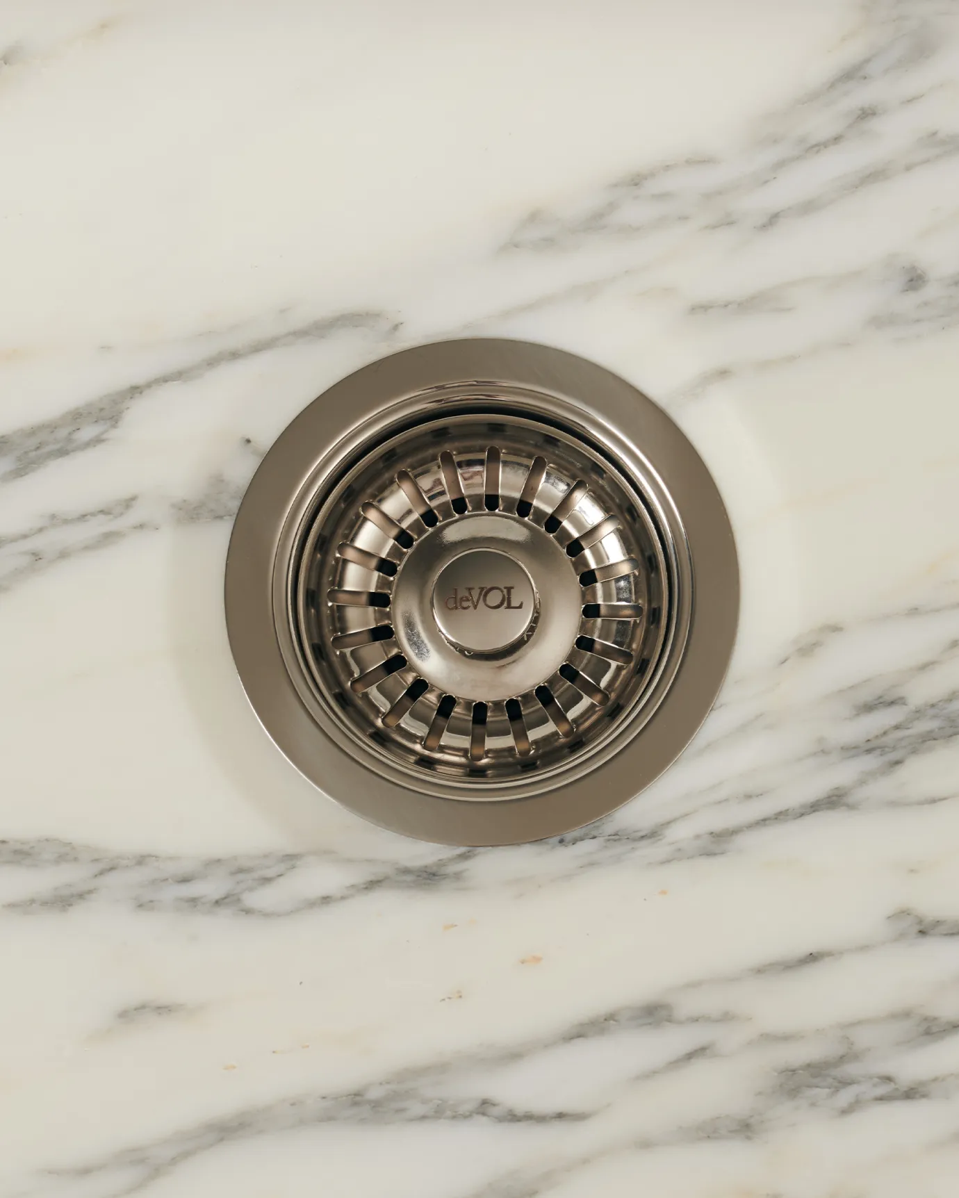 An overhead view of a basket waste strainer in a polished chrome finish, there is a small 'deVOL' logo in the middle of the central finial.