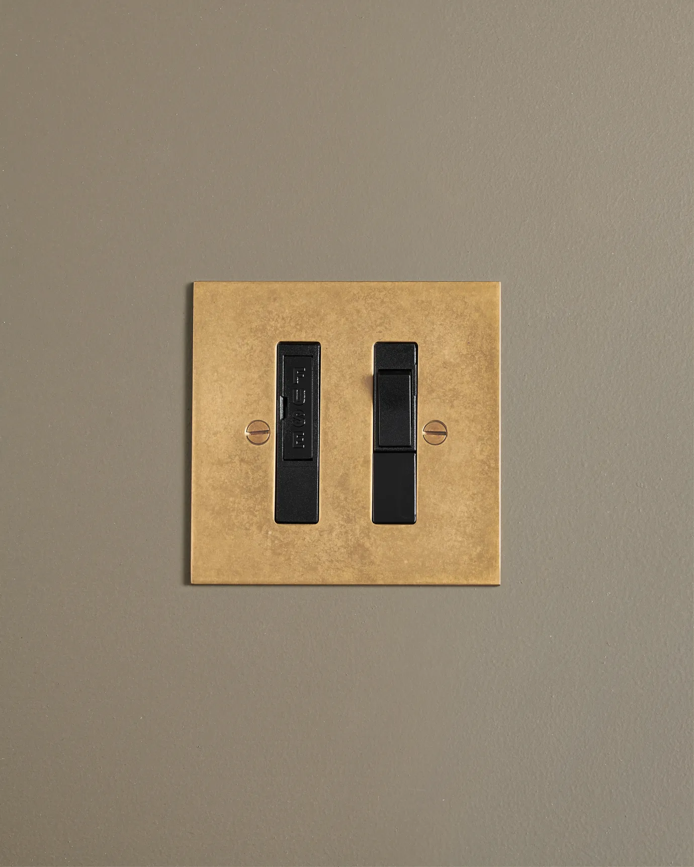 A straight-on view of a classic fused connection switch in a mottled aged brass finish.