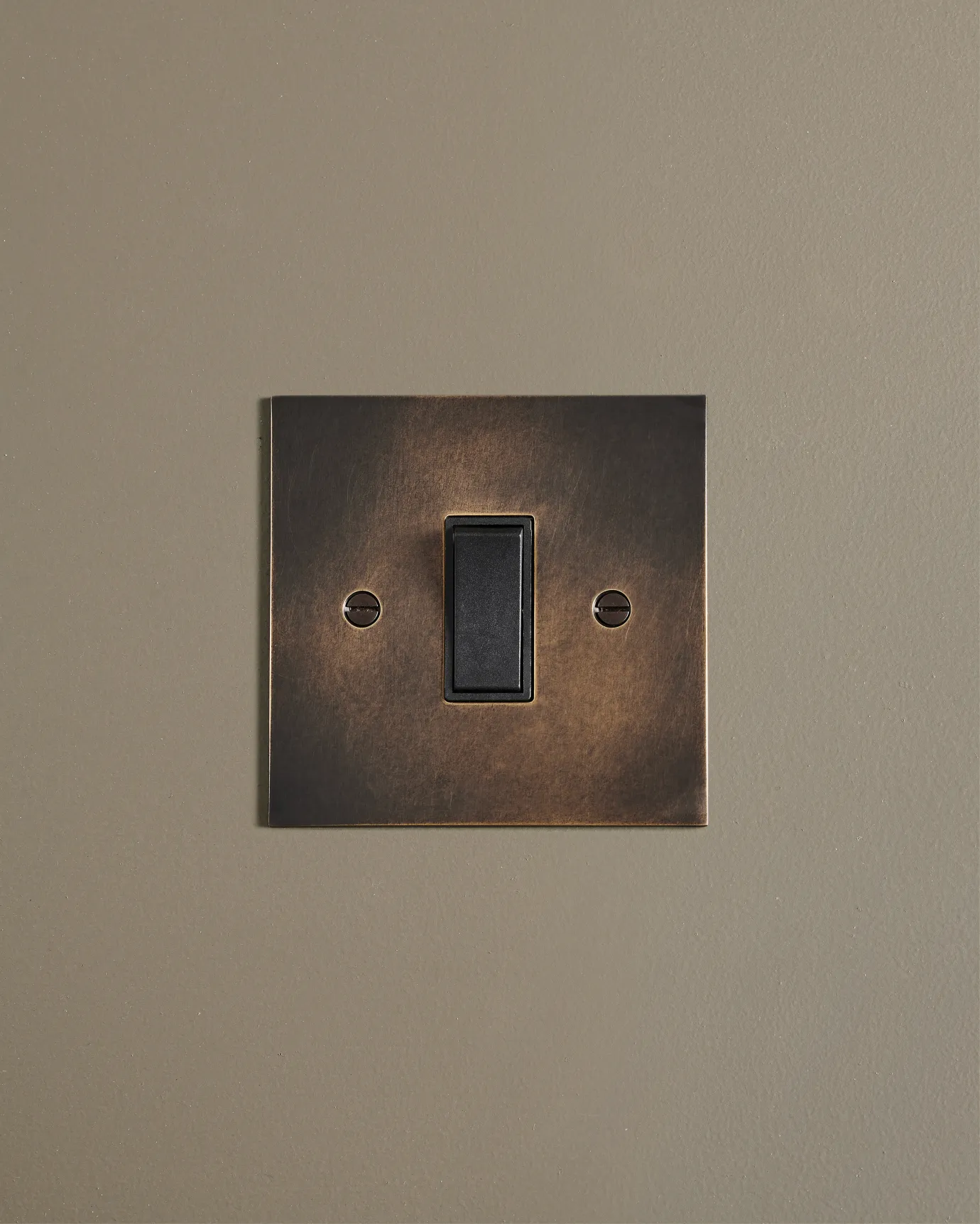 A straight-on view of a classic 20 amp switch in a dark oxidised brass finish.