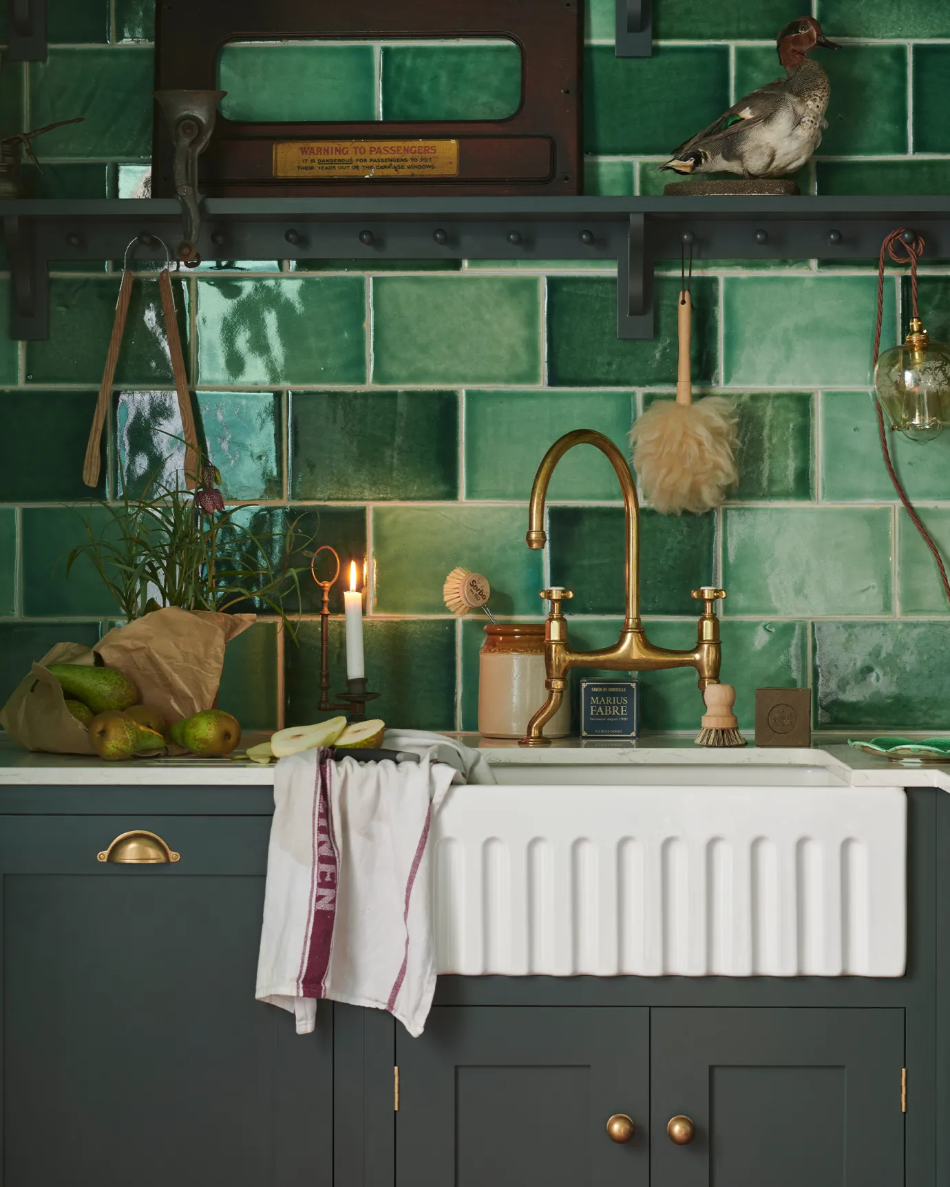 A detailed close-up of a Shaker-style kitchen, painted in 'Bakehouse Green' and fitted with glossy emerald green wall tiles.