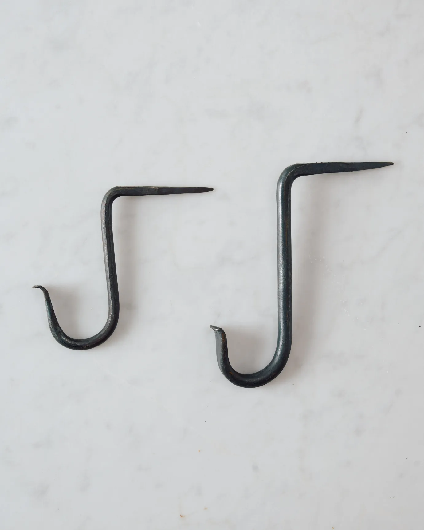 Two iron beam hooks with curled ends, one small and one large.