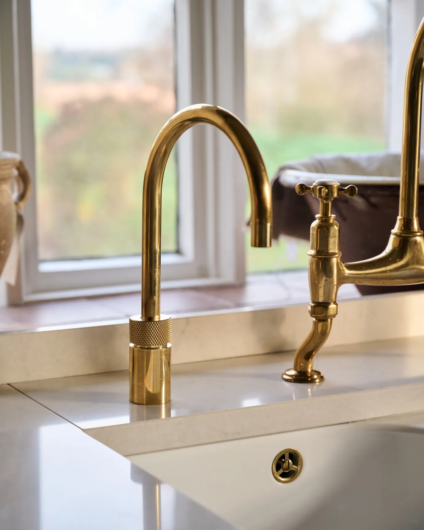 A contemporary-style brass tap with a minimal design on a light Silestone worktop.
